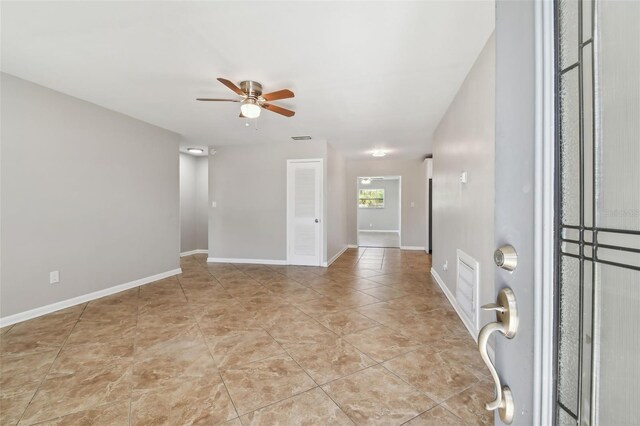 empty room with ceiling fan and light tile patterned floors