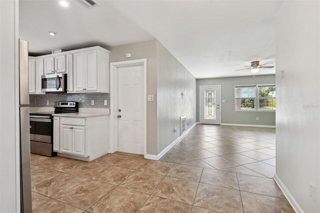 kitchen featuring decorative backsplash, stainless steel appliances, ceiling fan, white cabinets, and light tile patterned flooring