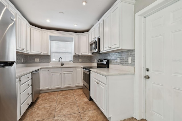 kitchen with sink, stainless steel appliances, light tile patterned floors, backsplash, and white cabinets