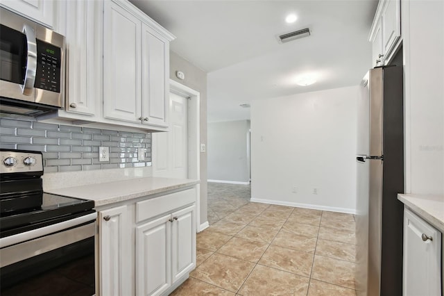 kitchen with white cabinets, decorative backsplash, light tile patterned floors, and appliances with stainless steel finishes