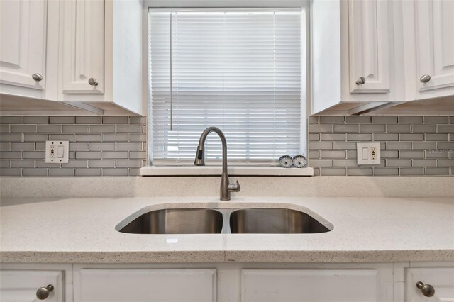 kitchen with white cabinets, light stone countertops, and sink