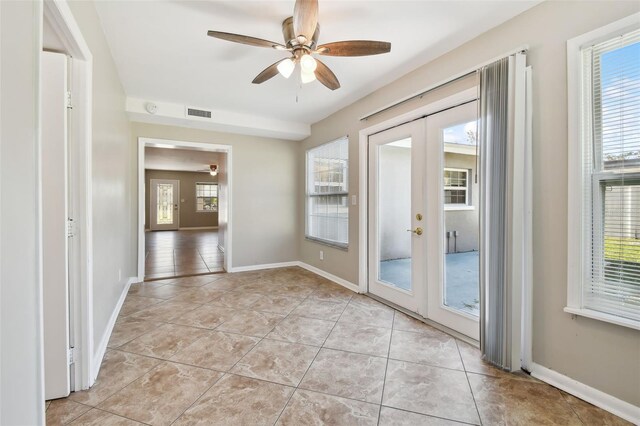 tiled empty room with french doors, plenty of natural light, and ceiling fan