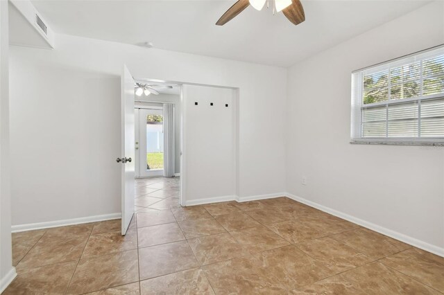 empty room with ceiling fan and light tile patterned flooring