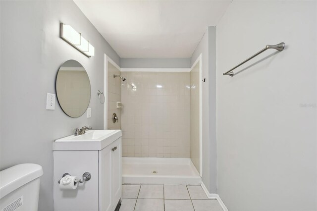 bathroom with tile patterned floors, vanity, toilet, and tiled shower