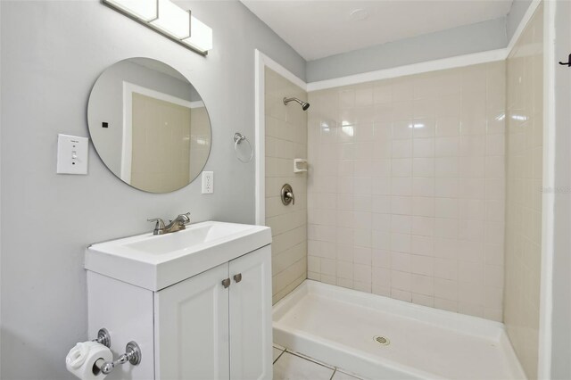 bathroom with tile patterned floors, vanity, and a tile shower