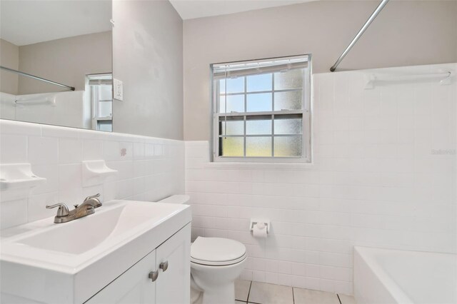 bathroom with tile patterned flooring, vanity, toilet, and tile walls