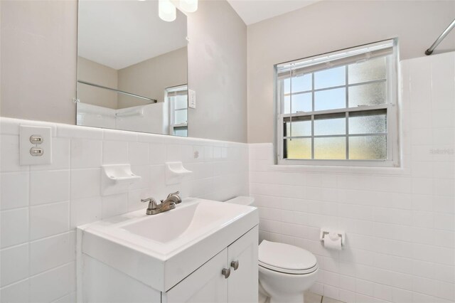 bathroom with vanity, toilet, and tile walls