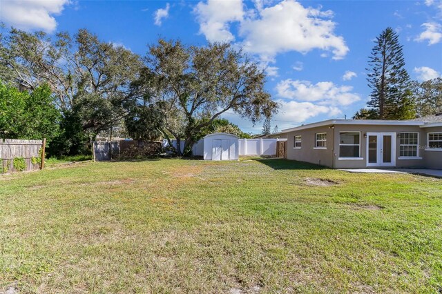 view of yard featuring a storage unit and french doors