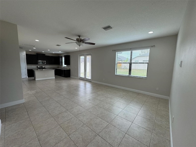 unfurnished living room with light tile patterned floors, a textured ceiling, and ceiling fan