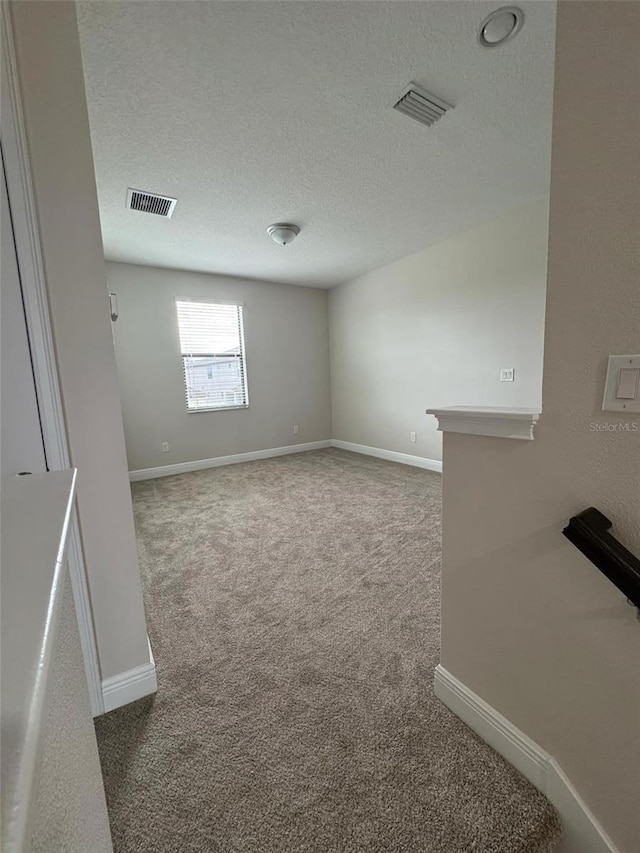 carpeted empty room with a textured ceiling