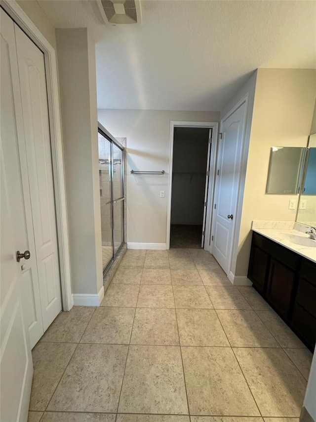 bathroom with tile patterned flooring, vanity, a textured ceiling, and walk in shower