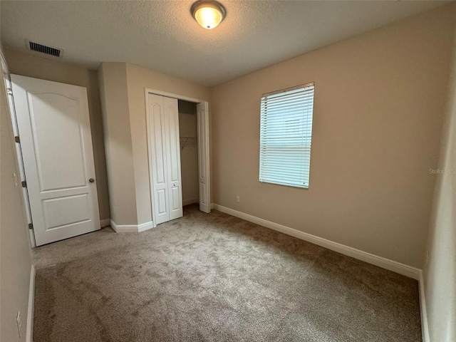 unfurnished bedroom featuring carpet flooring, a closet, and a textured ceiling