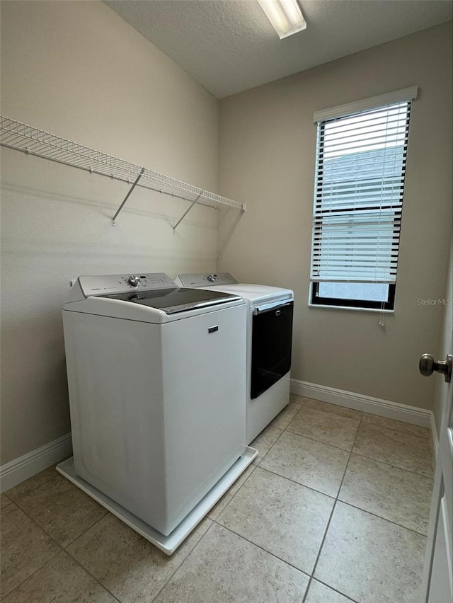 laundry room featuring light tile patterned floors, a textured ceiling, and separate washer and dryer