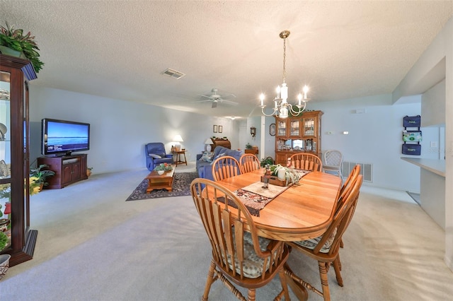 carpeted dining room with ceiling fan with notable chandelier and a textured ceiling