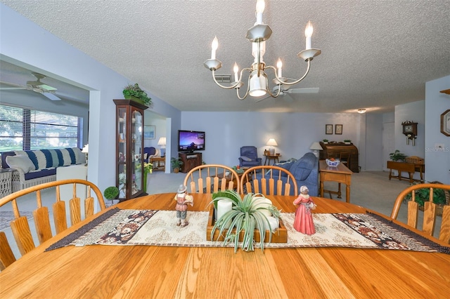 dining room with ceiling fan with notable chandelier, wood-type flooring, and a textured ceiling