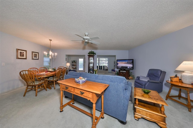 living room with ceiling fan with notable chandelier, light carpet, and a textured ceiling