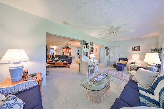 living room with a textured ceiling, ceiling fan, and light carpet