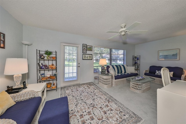 living room featuring light carpet, ceiling fan, and a textured ceiling