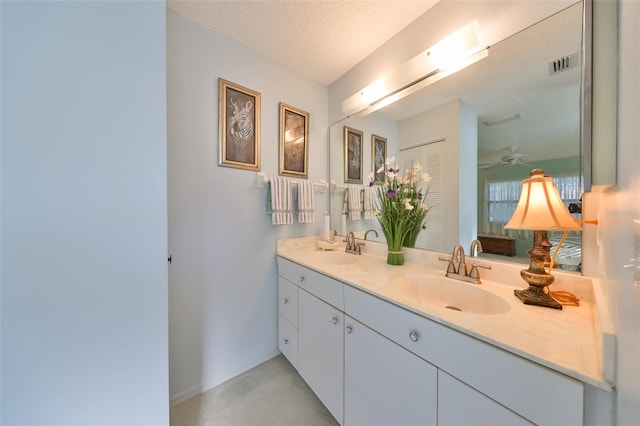 bathroom with vanity, ceiling fan, concrete flooring, and a textured ceiling