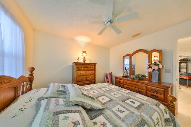 bedroom with ceiling fan, carpet floors, and a textured ceiling