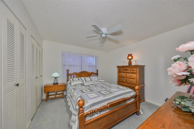 bedroom with ceiling fan, light colored carpet, and a textured ceiling