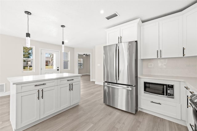 kitchen with white cabinetry, black microwave, and stainless steel refrigerator