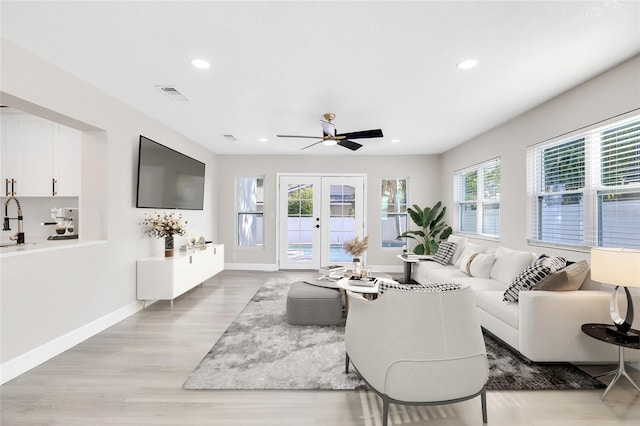 living room featuring french doors, light hardwood / wood-style flooring, ceiling fan, and sink