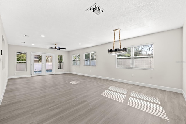 unfurnished living room with french doors, light hardwood / wood-style floors, ceiling fan, and a healthy amount of sunlight