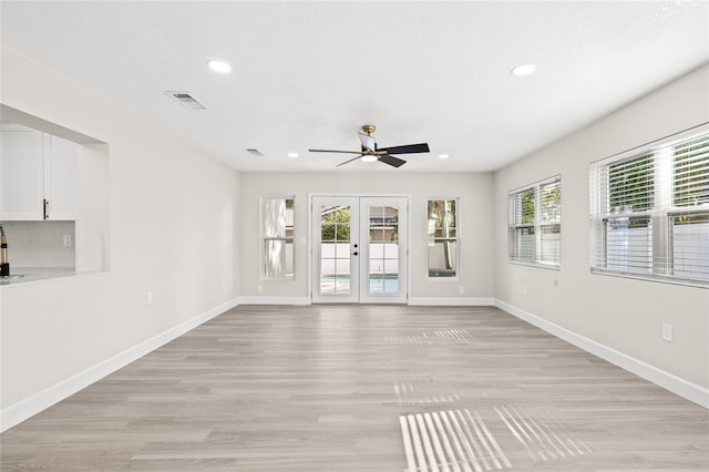 empty room with ceiling fan, french doors, and light wood-type flooring