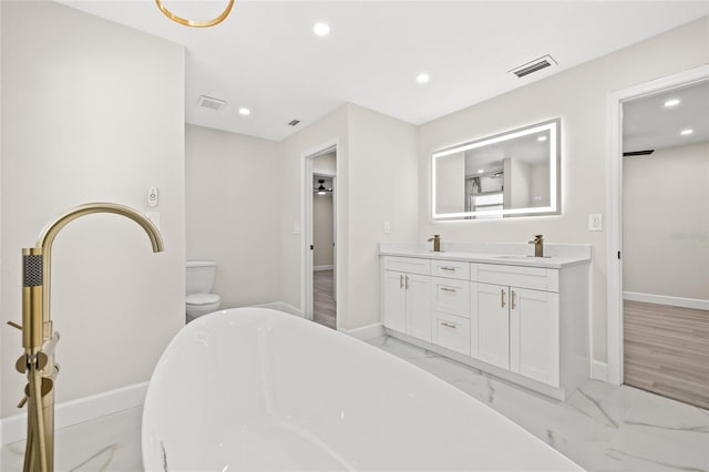 interior space featuring vanity, a tub to relax in, and toilet