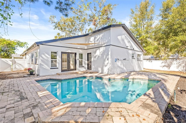 rear view of property featuring a fenced in pool, french doors, and a patio