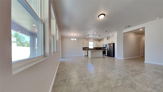 unfurnished living room featuring a chandelier and a textured ceiling