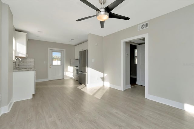 unfurnished living room featuring ceiling fan, light wood-type flooring, and sink