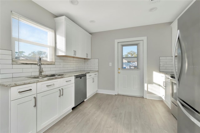 kitchen featuring white cabinets, appliances with stainless steel finishes, light stone countertops, and sink