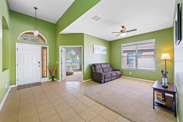 entryway with a wealth of natural light, light tile patterned floors, a textured ceiling, and ceiling fan