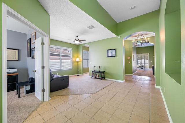 carpeted entryway featuring a textured ceiling and ceiling fan with notable chandelier