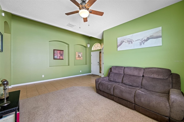 tiled living room with ceiling fan and a textured ceiling