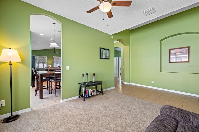 interior space featuring a textured ceiling, ceiling fan, light colored carpet, and lofted ceiling