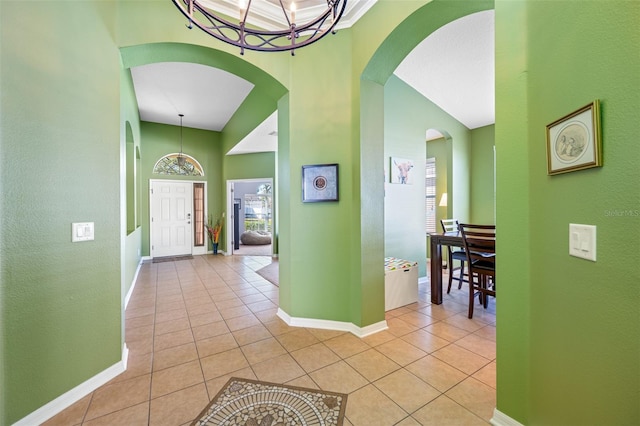 corridor featuring light tile patterned flooring, a high ceiling, and a chandelier