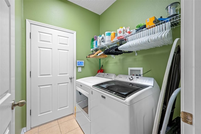 clothes washing area with light tile patterned flooring, a textured ceiling, and washing machine and clothes dryer