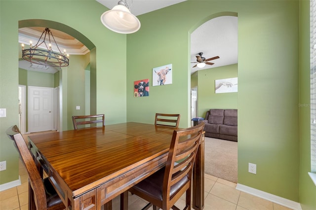 carpeted dining area featuring ceiling fan with notable chandelier, a raised ceiling, and ornamental molding