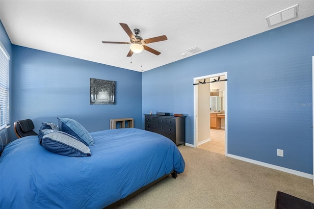 carpeted bedroom with a textured ceiling, connected bathroom, and ceiling fan