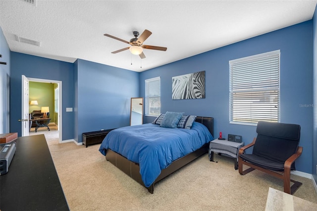 bedroom featuring a textured ceiling, ceiling fan, and light carpet