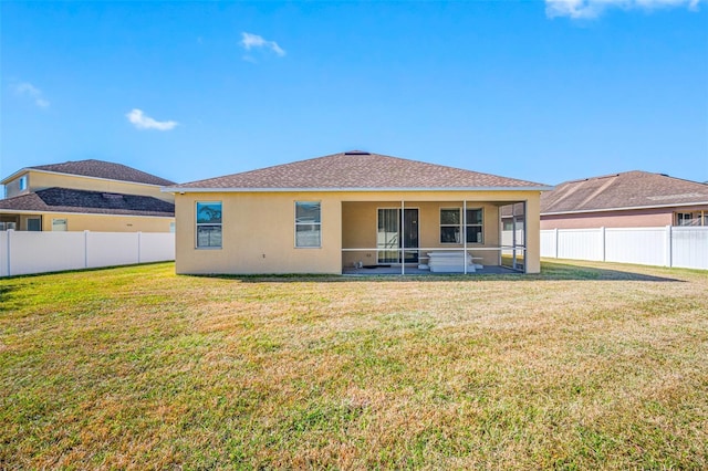 rear view of house featuring a lawn and a sunroom