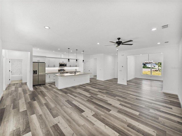 unfurnished living room with sink, ceiling fan, and light hardwood / wood-style floors