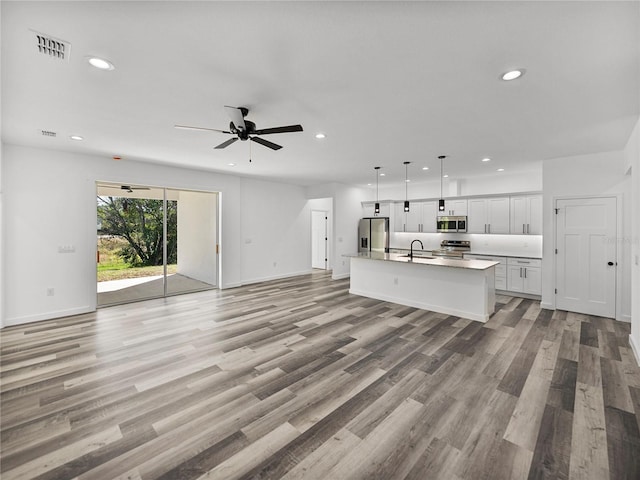 unfurnished living room with light hardwood / wood-style floors, sink, and ceiling fan