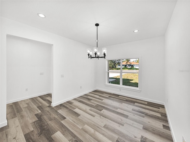 unfurnished dining area featuring hardwood / wood-style floors and an inviting chandelier