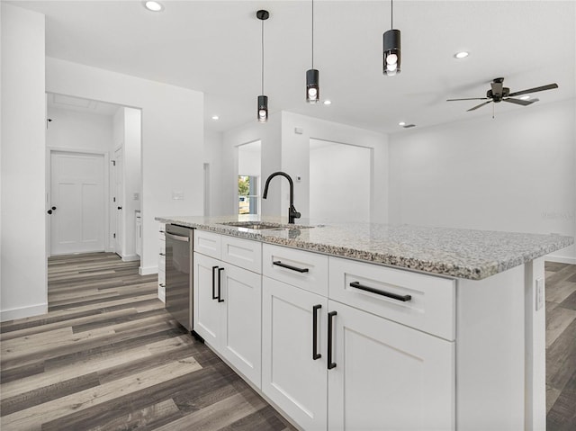 kitchen featuring stainless steel dishwasher, pendant lighting, sink, white cabinetry, and an island with sink