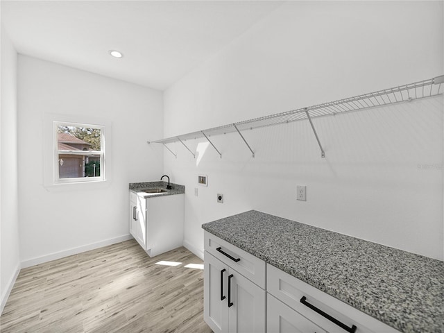 laundry area with cabinets, electric dryer hookup, sink, hookup for a washing machine, and light wood-type flooring