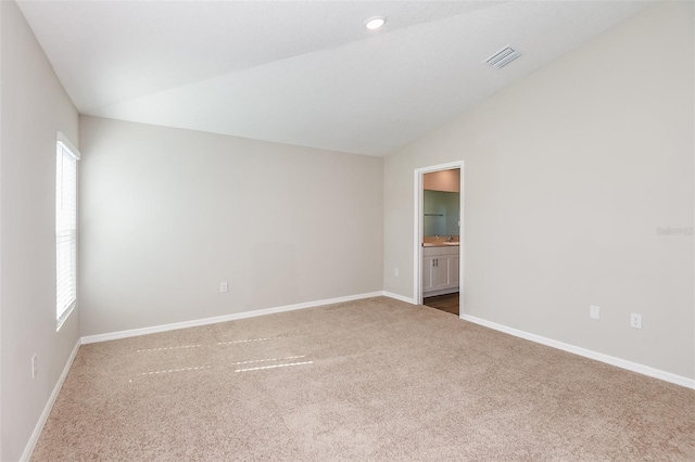 carpeted empty room with lofted ceiling, visible vents, and baseboards